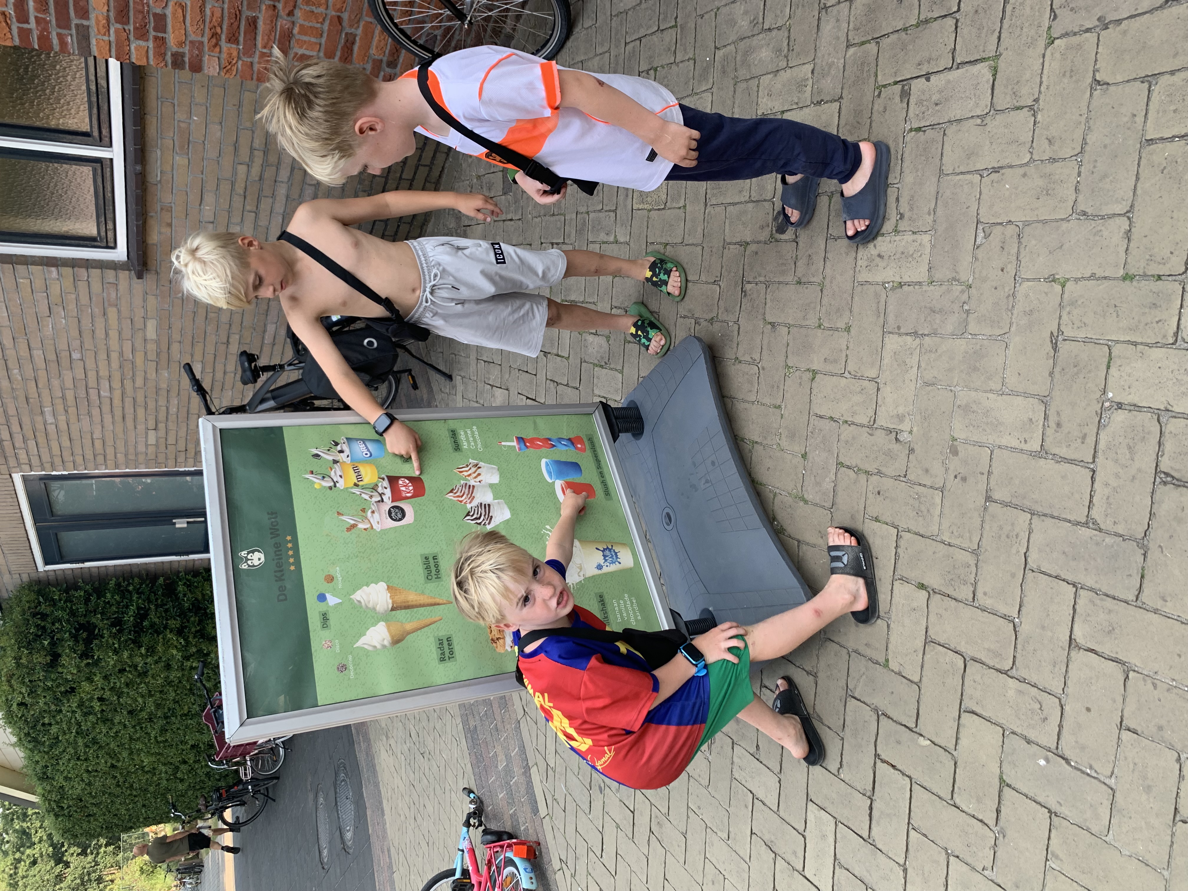 Kinderen bekijken het ijsaanbod op een menubord bij Camping De Kleine Wolf